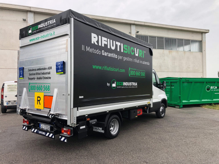 Furgone Rifiuti Sicuri Ecoindustria affiancato a container verdi di stoccaggio rifiuti.